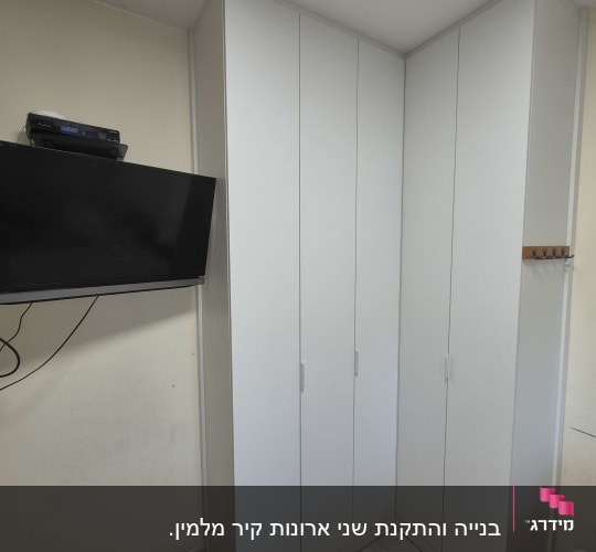 ארון לבן בפינת חדר עם טלוויזיה על הקיר
